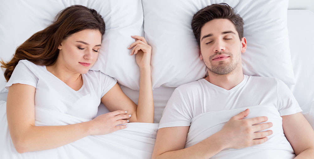 A couple happily using a THREE Duvets dual tog duvet.