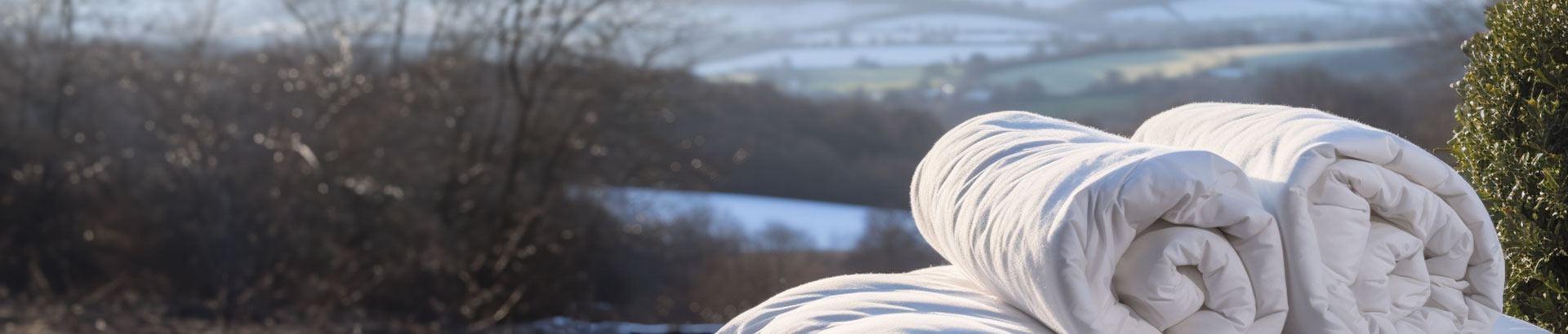 Eco-friendly Botanic Lightweight Duvet from THREE Duvets draped over a hay bale, highlighting plant-based fibers in a natural farm setting.