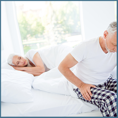 Couple in bed struggling to sleep due to different warmth preferences.