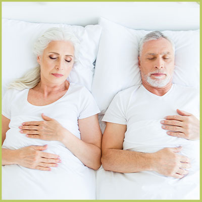 Happy couple sleeping comfortably under a THREE Duvets shared duvet