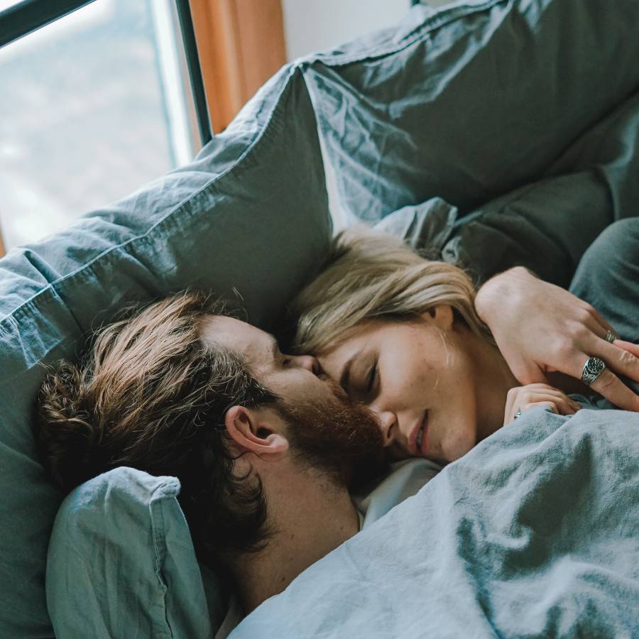 Couple relaxing in bed, showing the superior comfort and warmth provided by THREE Duvets.