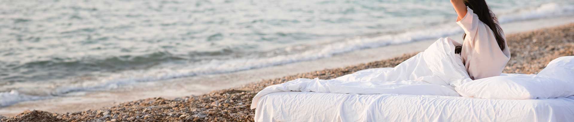 Someone in bed enjoying our lightweight duvets at the beach